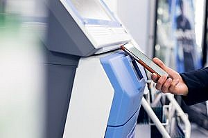 Woman paying with a mobile phone at a kiosk